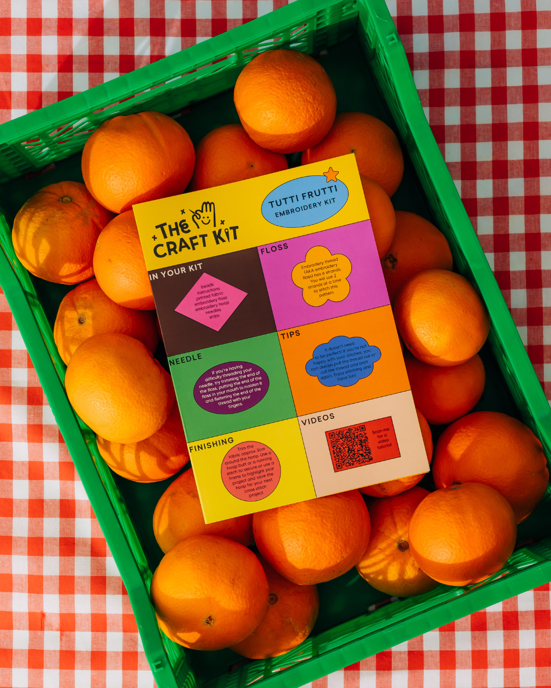 Colorful 'The Craft Kit' box among oranges on a red and white checkered tablecloth